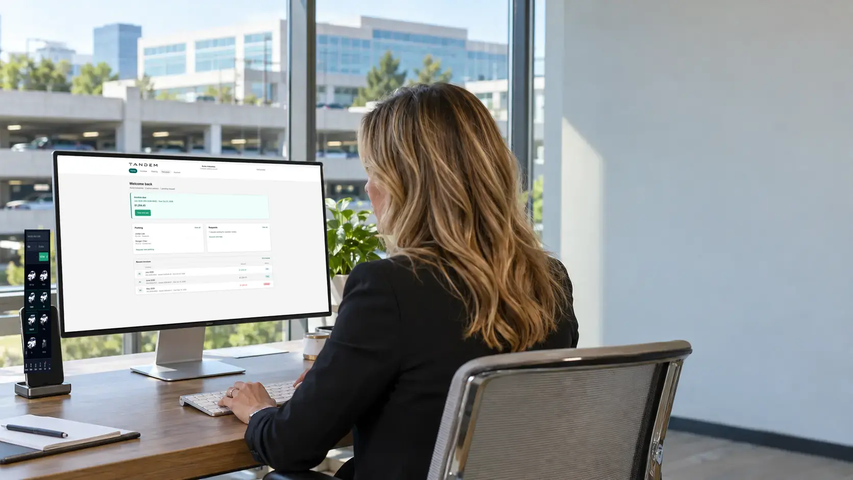 Company contact using the Tandem portal on a desktop monitor while the dark mobile parker portal displays a vehicle list
